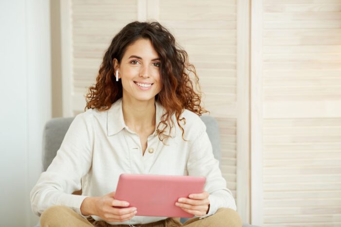 Person sitzt vor Tablet oder Laptop, frontal aufgenommen, heller Hintergrund, modernes Arbeitsumfeld