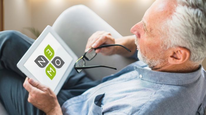 Person liegt seitlich auf einem Sofa und nutzt ein Tablet, Nahaufnahme der Hände mit digitalem Gerät in ruhiger Umgebung